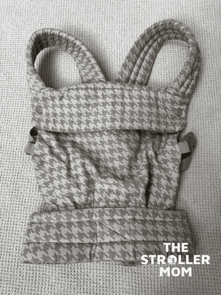 Flat lay of the Mabe Monarch Carrier in houndstooth showing the full carrier structure, padded straps, waistband, and snap hardware