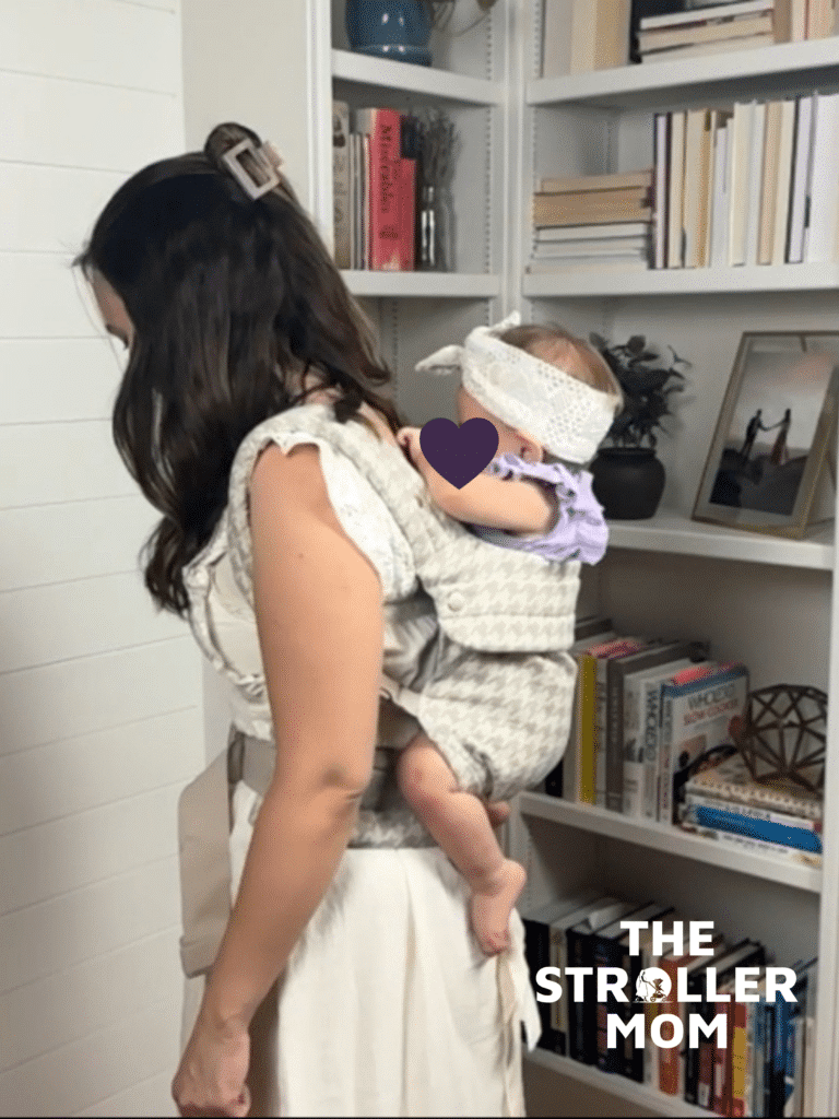 Mom demonstrating the back carry position in the Mabe Monarch Carrier in houndstooth with a toddler