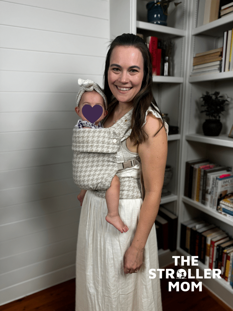 Side view of mom wearing baby in the Mabe Monarch Carrier in houndstooth, showing the front inward-facing position with head support panel snapped up