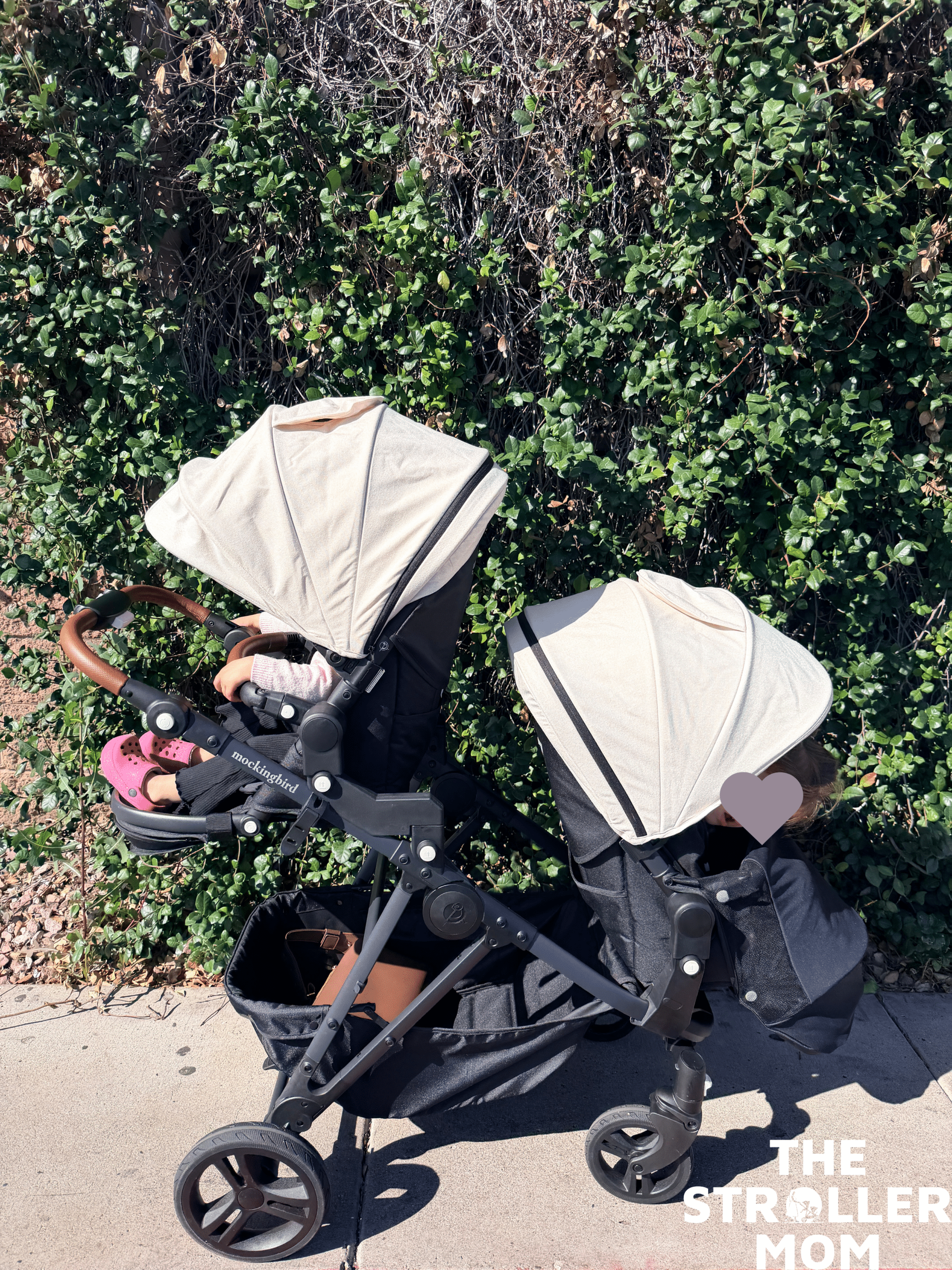 Mockingbird 3.0 Single to Double stroller with one seat parent facing and the other world facing in front of a bush