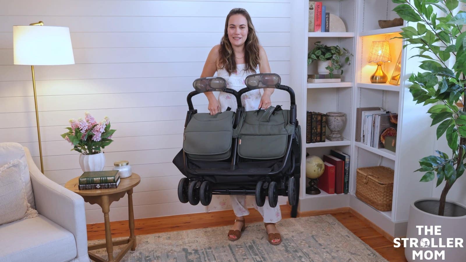 Emily holding the folded Zoe Twin V3 in front of her, showing its size and wheels.